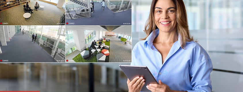 Woman holding tablet in modern office, with security camera feeds displayed showing various areas, emphasizing office security and visitor management during back-to-school season.